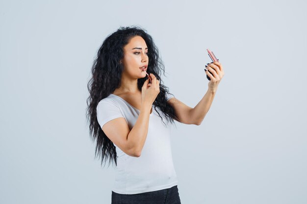 Beautiful brunette woman applying lipstick