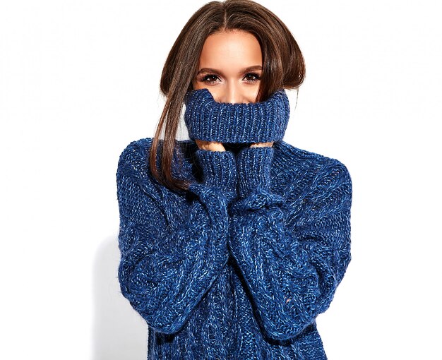 beautiful brunette woman in casual blue sweater with bright makeup and red lips on white. Covering her face