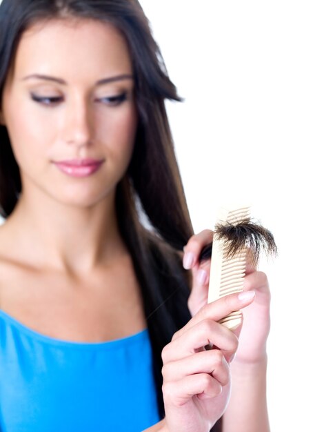 Beautiful brunette woman combing and looking on the ends of her long hair - foreground