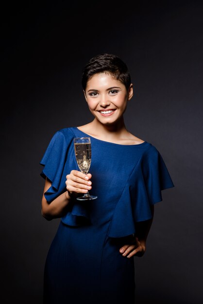 Beautiful brunette woman in evening dress smiling, holding champaign glass