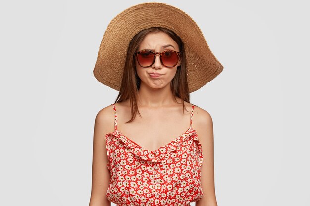 夏の帽子、ドレス、不満の唇を財布、不快感を感じる美しいブルネットの女性