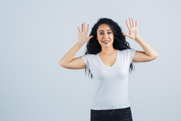 ジェスチャーをしている白いTシャツの美しいブルネットの女性