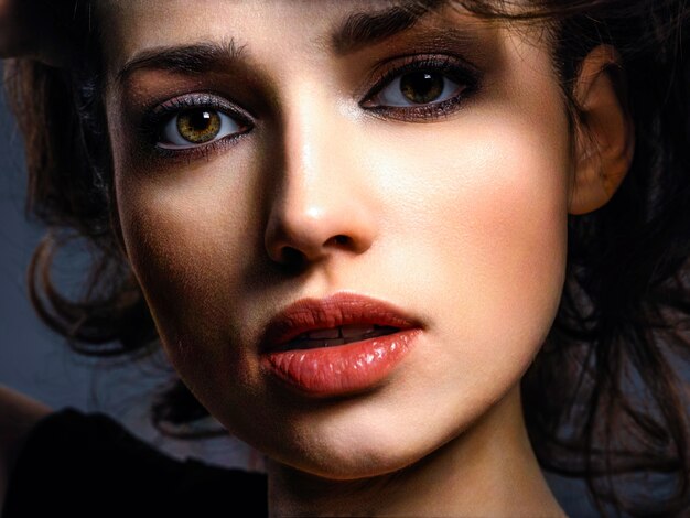 Beautiful brunette woman with  brown eyes. Fashion model with a smokey makeup. Closeup portrait of a pretty woman looks at camera.