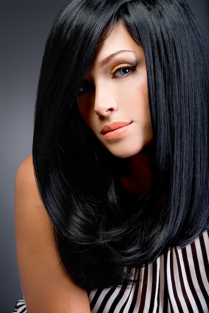 Foto gratuita bella donna castana con capelli lisci neri lunghi che posa allo studio