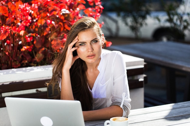 Beautiful brunette works with laptop outside