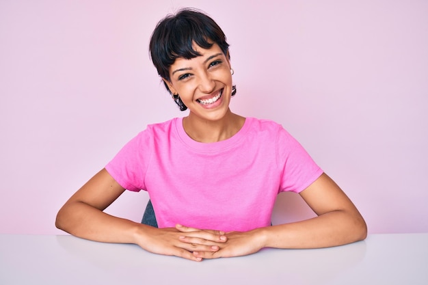 Beautiful brunettte woman wearing casual clothes over pink background looking positive and happy standing and smiling with a confident smile showing teeth