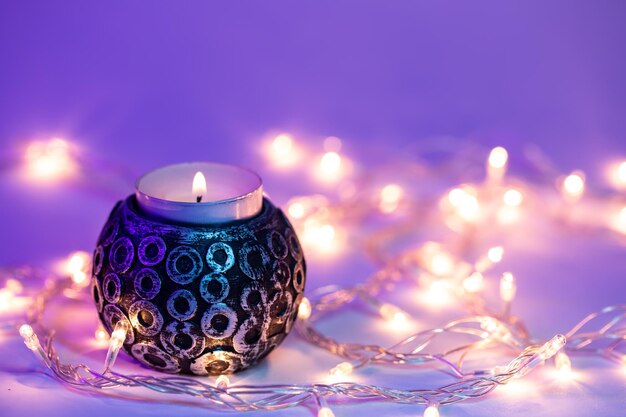 Free photo beautiful burning candle and garlands with neon lighting