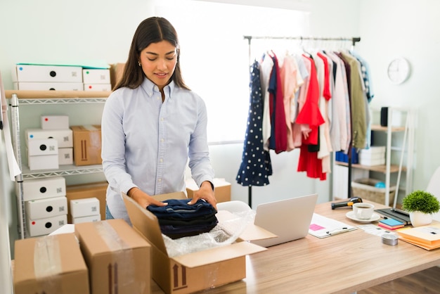 Beautiful business owner with a lot of online orders. Female entrepreneur preparing the clothes to put on packages