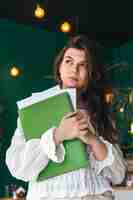 Бесплатное фото Красивая деловая женщина с папкой бумаг в зеленом интерьере