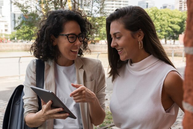 Beautiful business women looking at a tablet outside