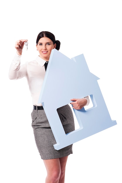 Beautiful businesswoman holding house sign and keys for him