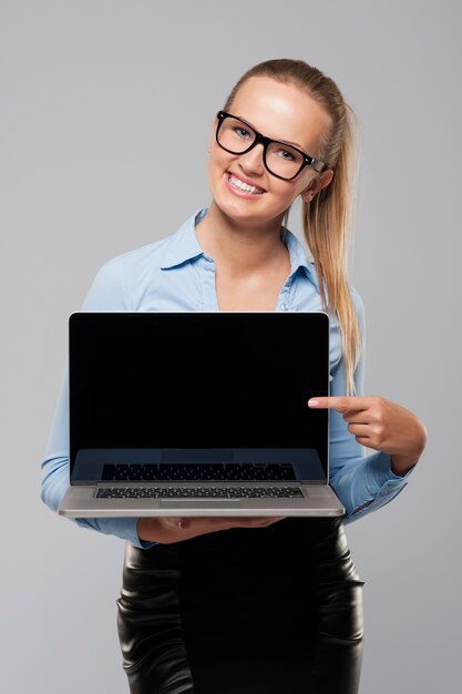 Beautiful businesswoman showing on blank screen of laptop