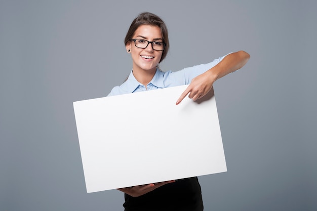 Beautiful businesswoman showing on empty whiteboard