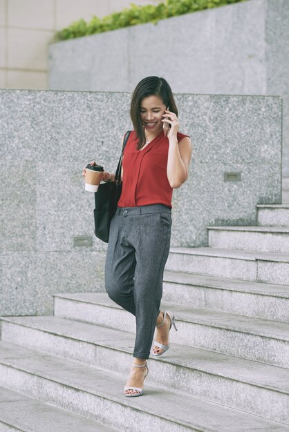 Beautiful career girl going down the stairs talking on the phone