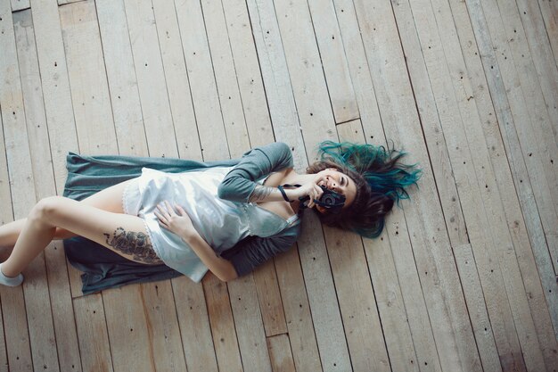 Красивая беззаботная молодая случайная женщина, лежа на деревянном полу