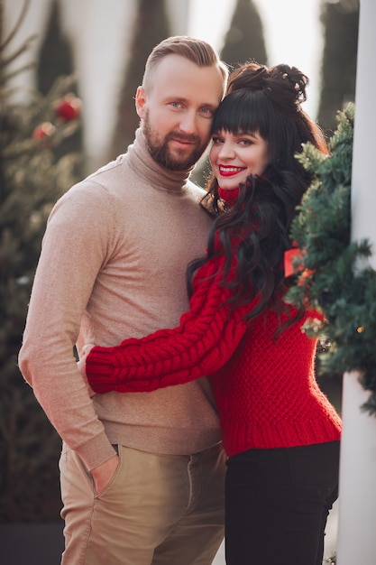 Beautiful caucasian couple in love cuddles together on the street in Christmas Eve