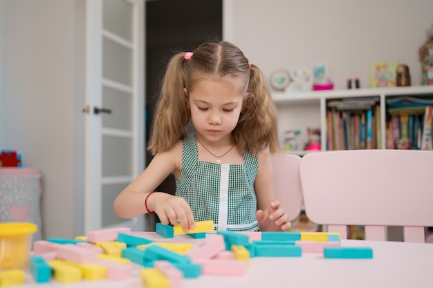 Beautiful caucasian girl playing with wooden multi-colored blocks