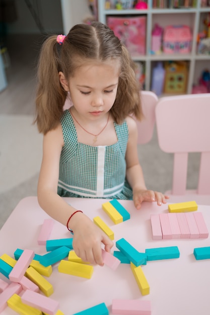 Красивая кавказская девушка играет с деревянными разноцветными блоками