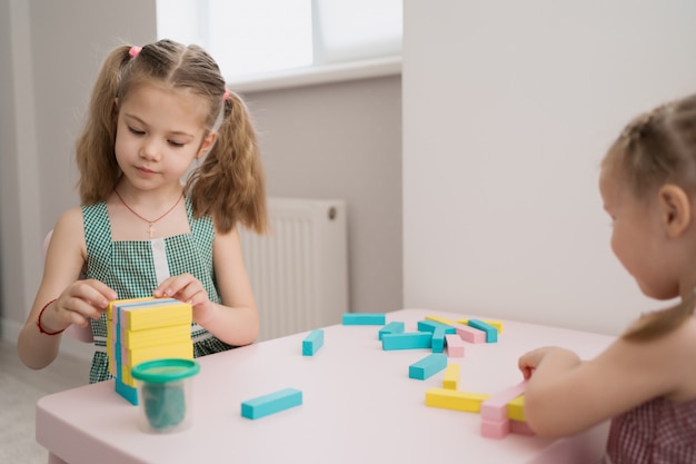 Beautiful caucasian girls playing with wooden multi-colored blocks