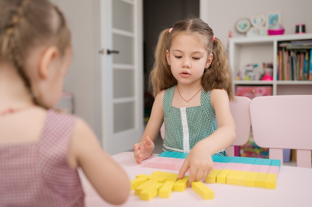 Beautiful caucasian girls playing with wooden multi-colored blocks