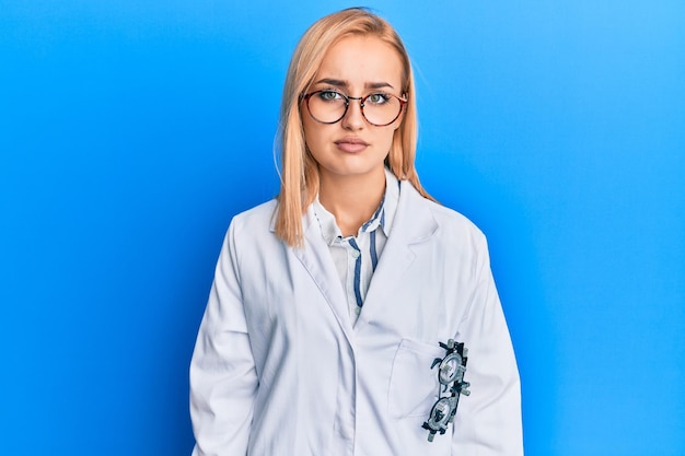 Beautiful caucasian oculist woman wearing robe and optometry glasses with serious expression on face. simple and natural looking at the camera.