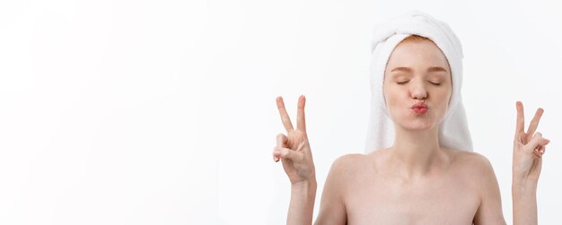 Beautiful caucasian woman applying mask on her face with two fingers sign white background