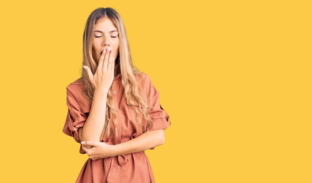 Beautiful caucasian woman with blonde hair wearing summer jumpsuit bored yawning tired covering mouth with hand. restless and sleepiness.