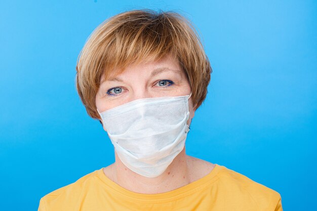 Beautiful caucasian woman with special medical mask is happy, portrait isolated on blue background