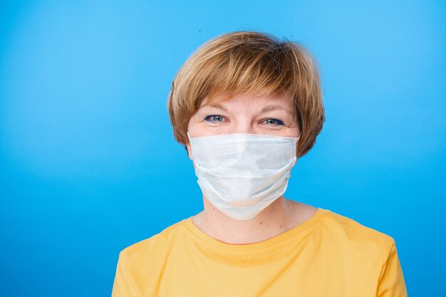 Beautiful caucasian woman with special medical mask is happy, portrait isolated on blue background