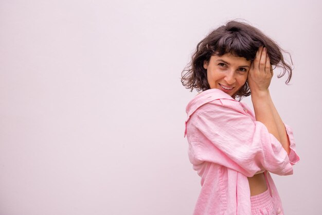 Beautiful caucasian young brunette girl in pink clothes looks at camera on white background with place for text Lifestyle concept