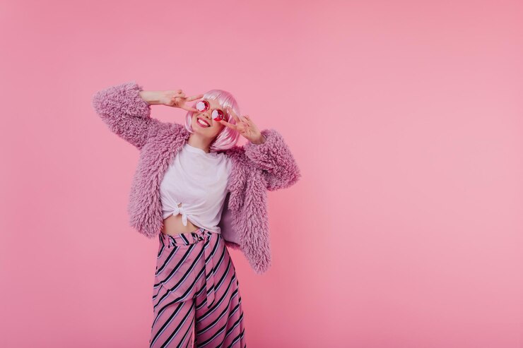 Free Photo beautiful caucasian young woman in striped pants looking up during photoshoot indoor portrait of smiling girl in sunglasses having fun in studio