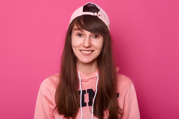 Beautiful charming girl wears pink hoodie and visor cap back.