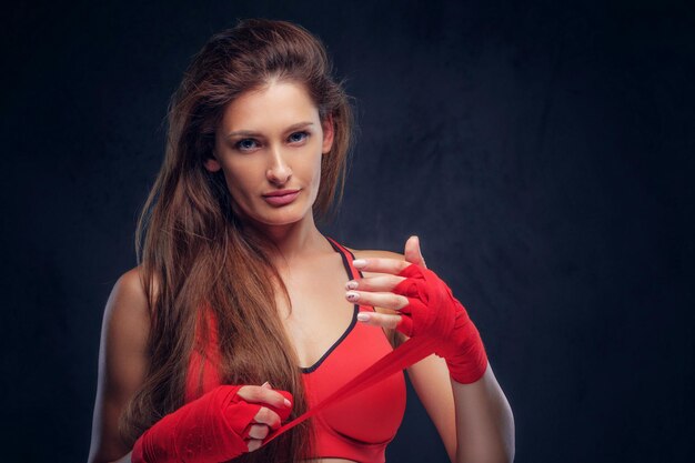 Beautiful cheerful woman in red bra is wearing her gloves before boxing.
