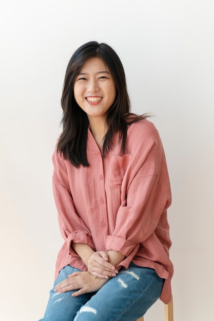 Free photo beautiful cheerful woman sitting by a white wall