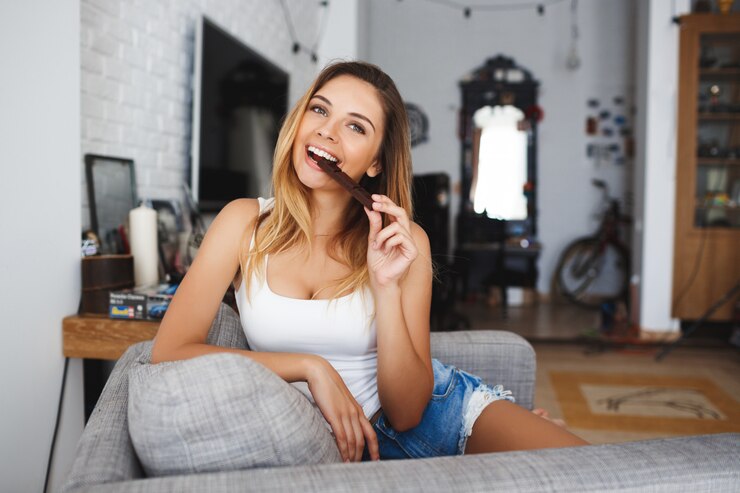 Free Photo beautiful cheerful young woman eating bite of chocolate