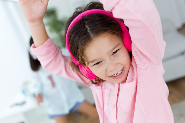 Красивый ребенок слушает музыку и танцует дома.