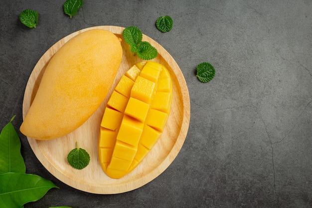 Beautiful chopped ripe mango on dark wooden surface
