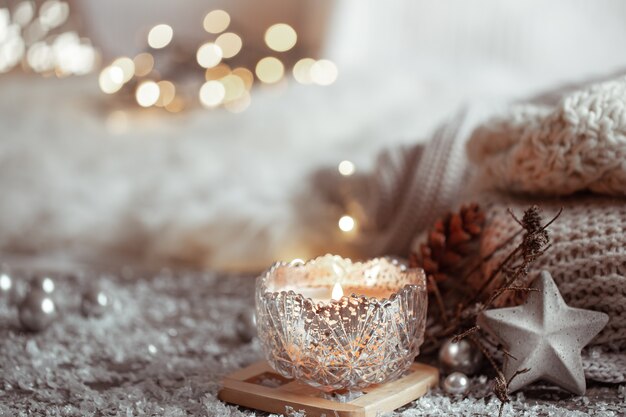 Красивая рождественская свеча в подсвечнике на светлом размытом фоне. Понятие домашнего уюта и тепла.