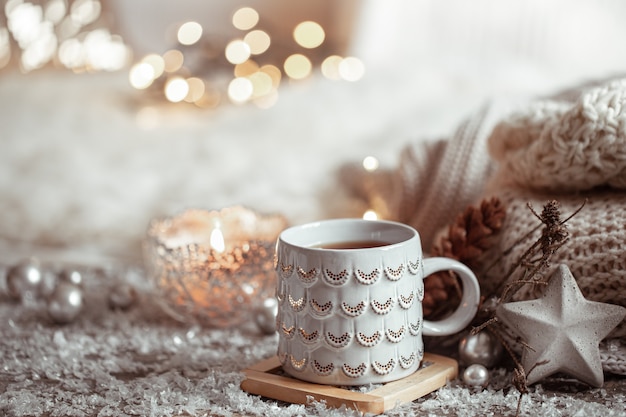 Beautiful Christmas cup with a hot drink on a light blurred wall. The concept of home comfort and warmth.