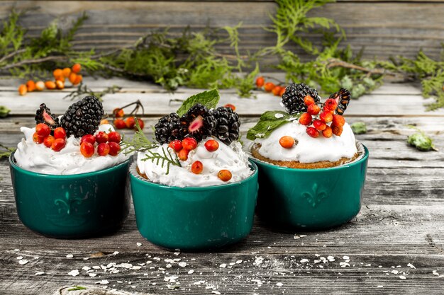 beautiful Christmas cupcake with cream and berry on wooden wall cinnamon cones