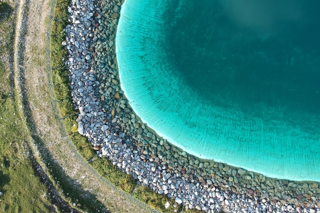 Beautiful clear blue lake in a green field shot from above