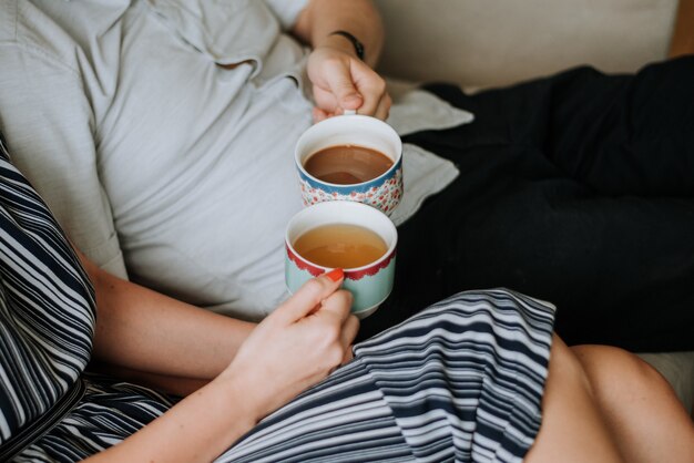 Beautiful closeup of a couple holding two cups of tea in their hands