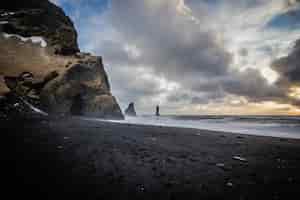 Foto gratuita splendida costa del mare a vik, islanda con nuvole e rocce mozzafiato sul lato