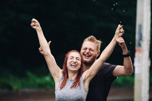 雨の日の背景で人生を楽しんでいる美しいカップル