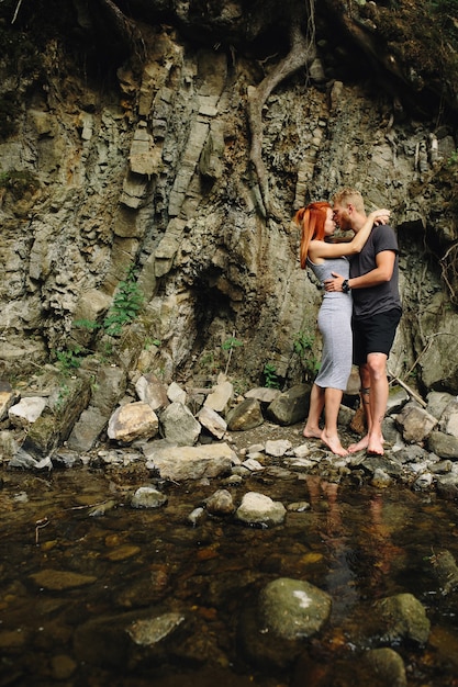 Beautiful couple hugging each other near a mountain river