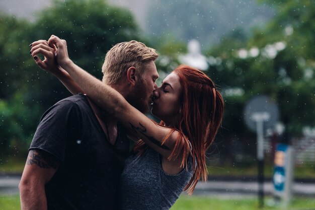 雨の中で外でキスする美しいカップル