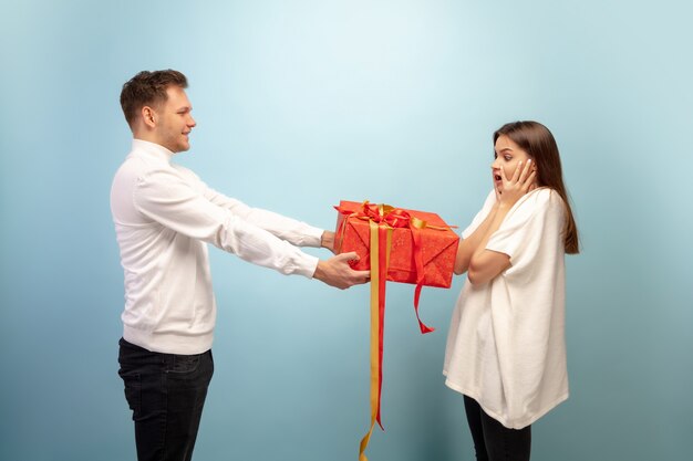 Beautiful couple in love on blue studio wall