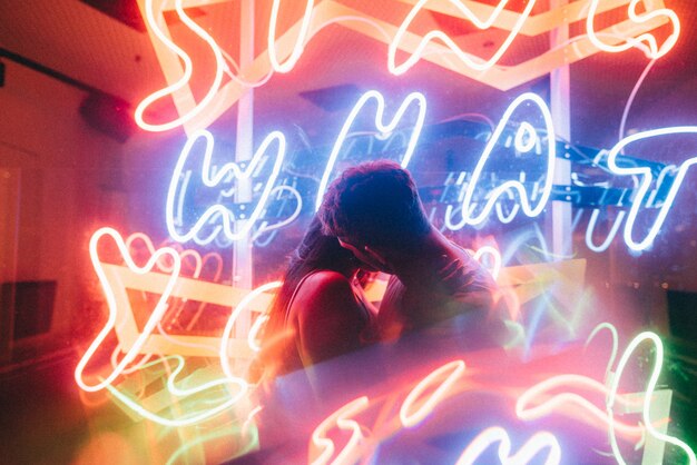 Beautiful couple loving each other surrounded by neon lights shot with a slow shutter