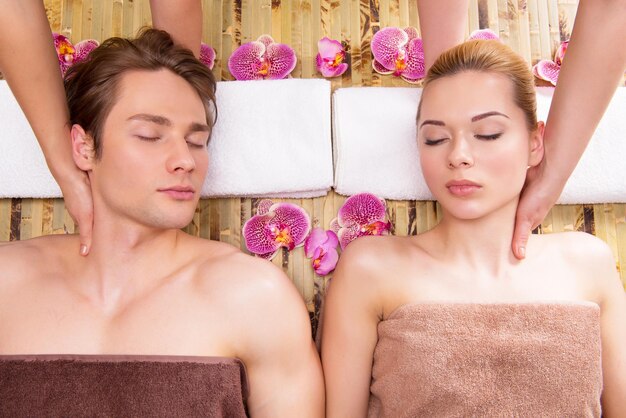 Красивая пара, лежа в спа-салоне, вместе наслаждаясь массажем головы.