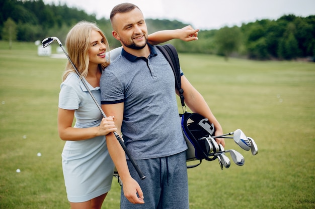 ゴルフコースでゴルフをする美しいカップル